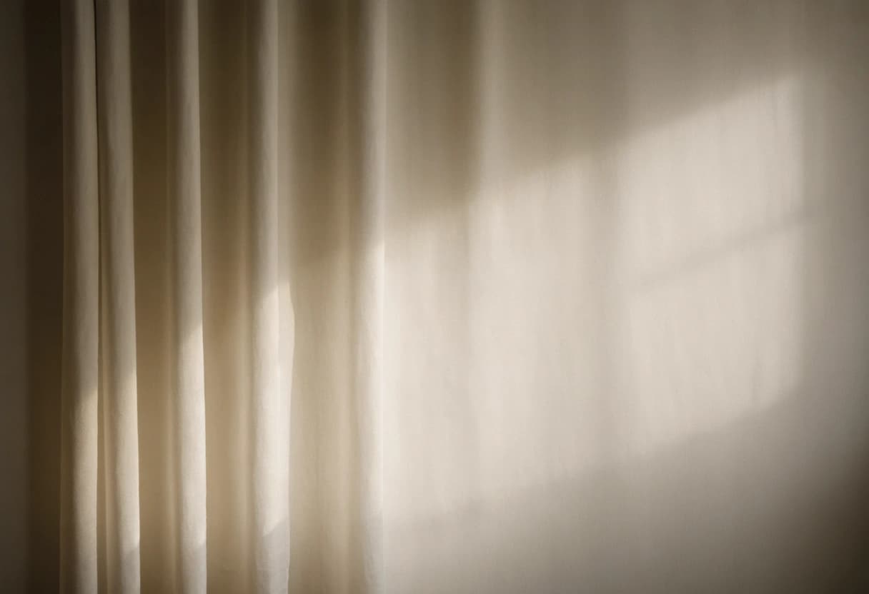 Morning light falling through a sheer curtain onto a pale plaster wall